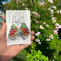 a person holding up a playing card with a moth on it